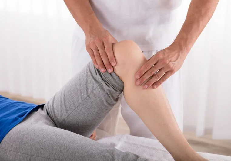 Physiotherapist Giving Knee Exercise To Woman